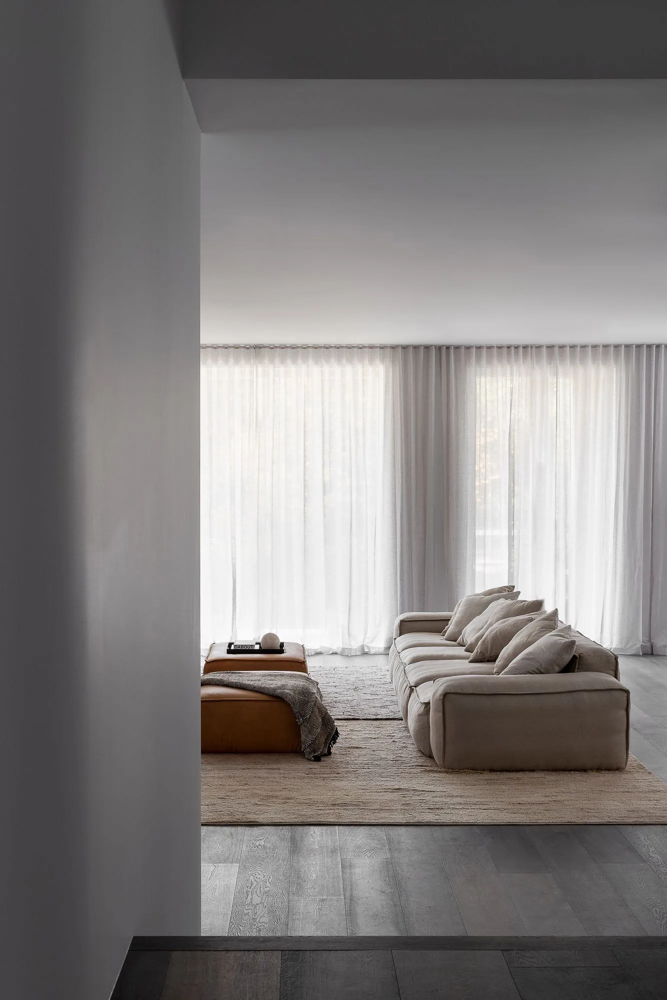 A modern living room featuring a fabric couch and leather ottoman.