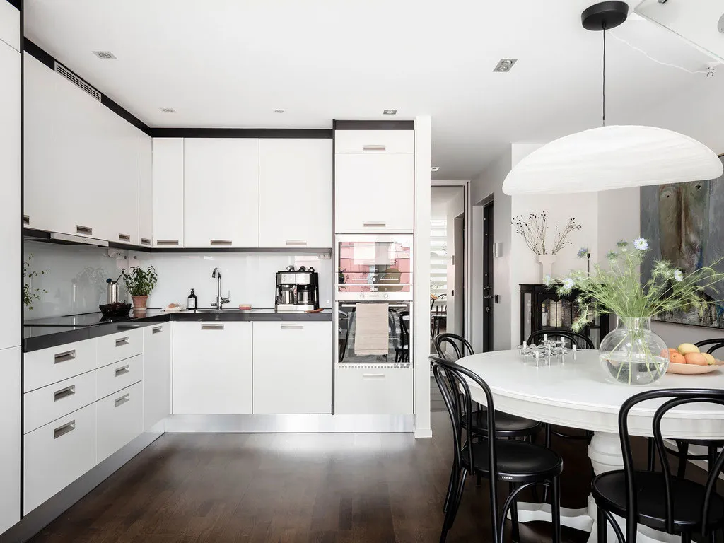 Modern minimalist kitchen with white cabinetry and dark wood flooring.