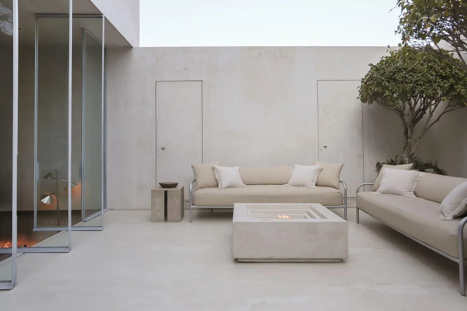 A minimalist outdoor living space featuring concrete, metal, and wooden elements.