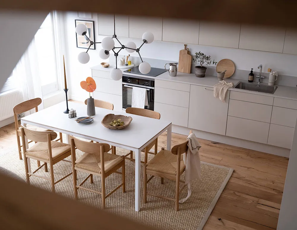 Modern minimalist kitchen with white cabinets, wood counter, and minimalist table setting.