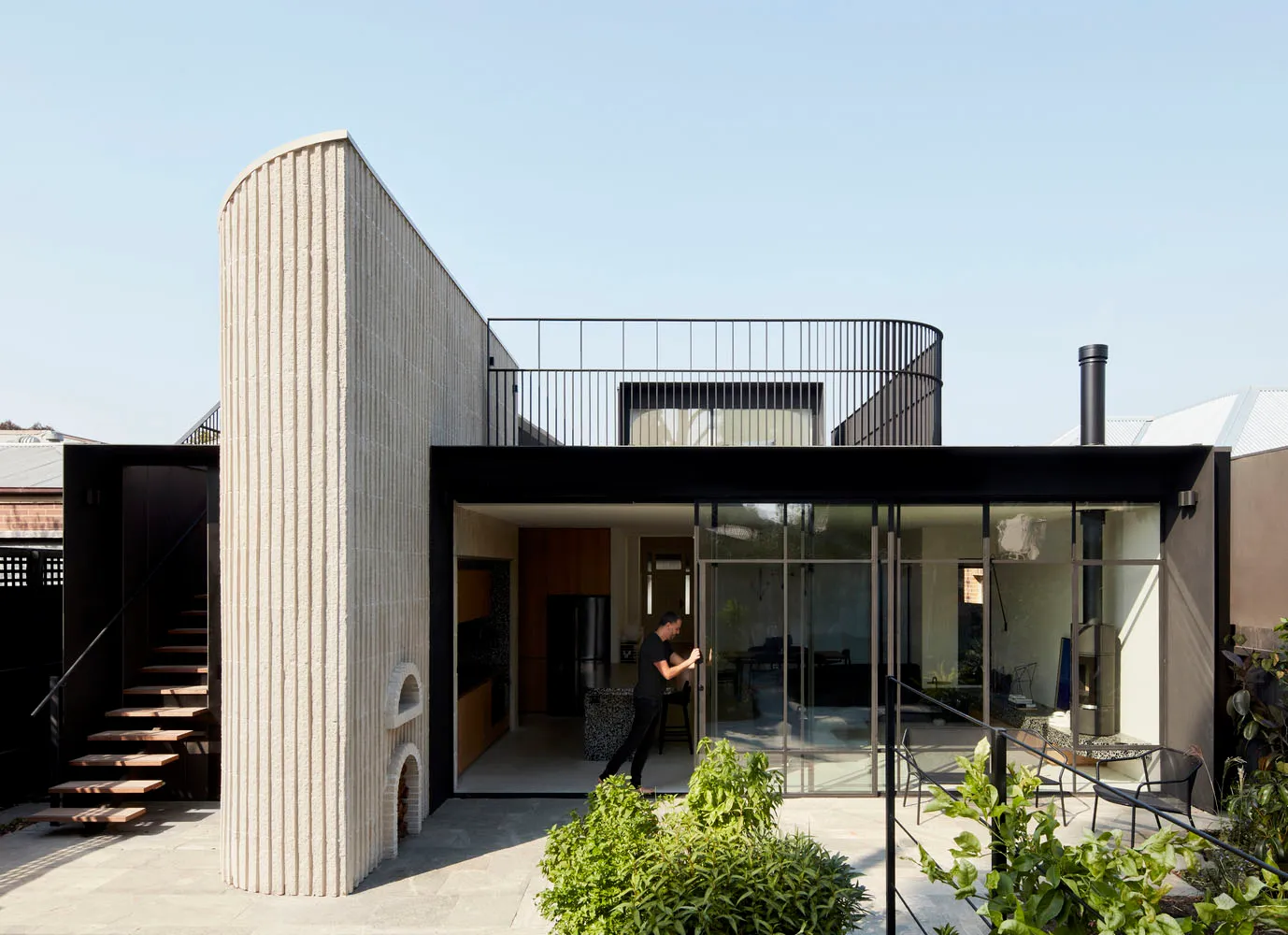 A modern home featuring a unique curved wall made of beige concrete.