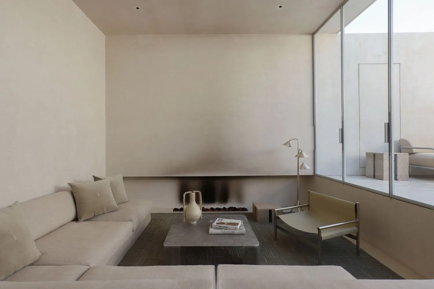 A minimalist living room with neutral-tones furniture and a fireplace.
