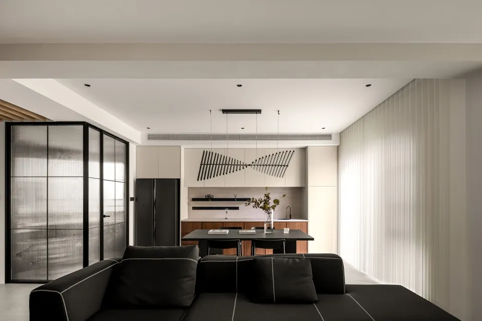 Modern, minimalist living room with black furniture, white walls, and a large window.