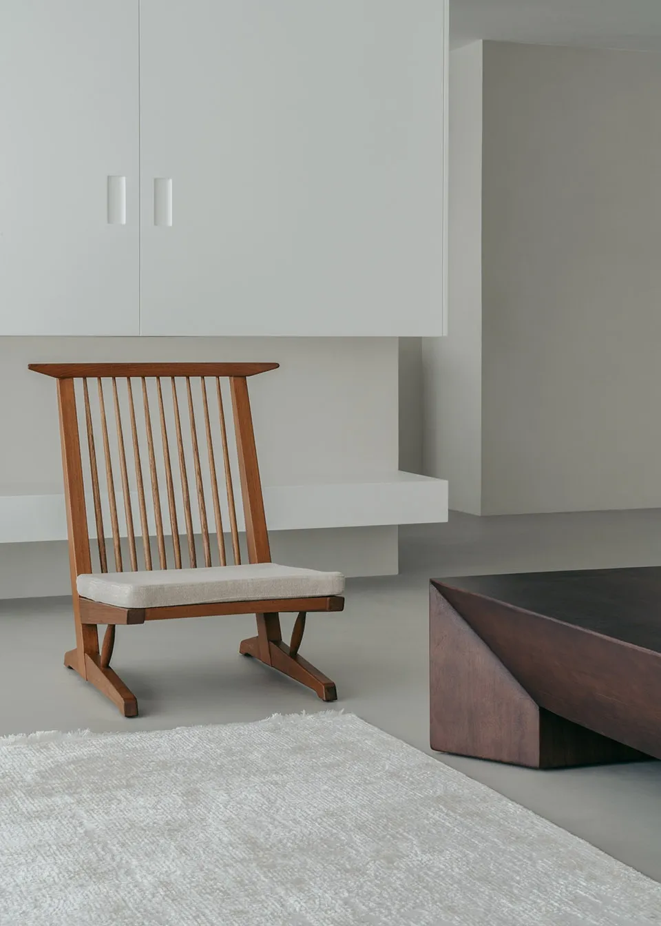 A minimalist living room featuring wooden furniture with a low coffee table and a cushioned chair.