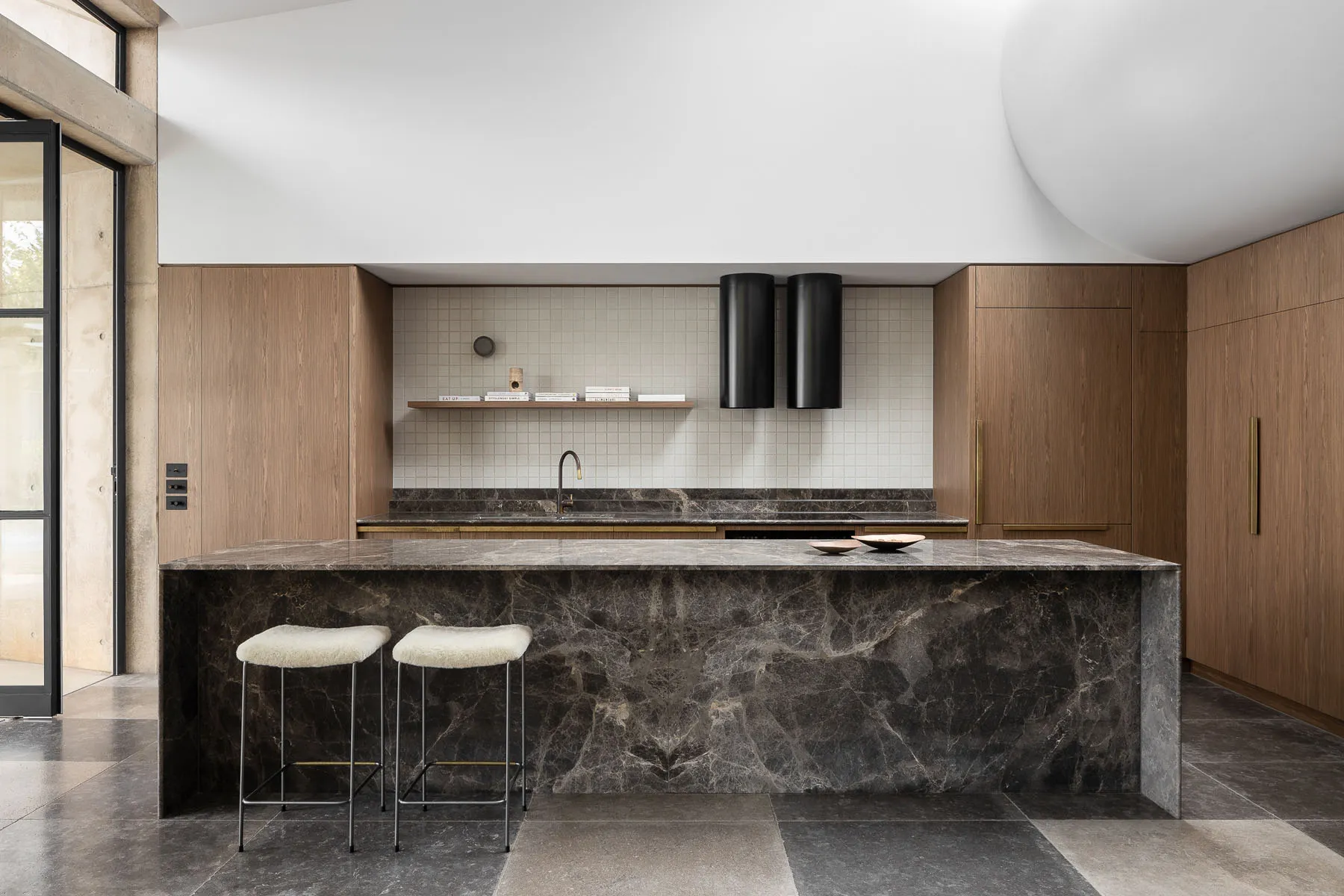 A modern kitchen with a marble island and wooden cabinets.