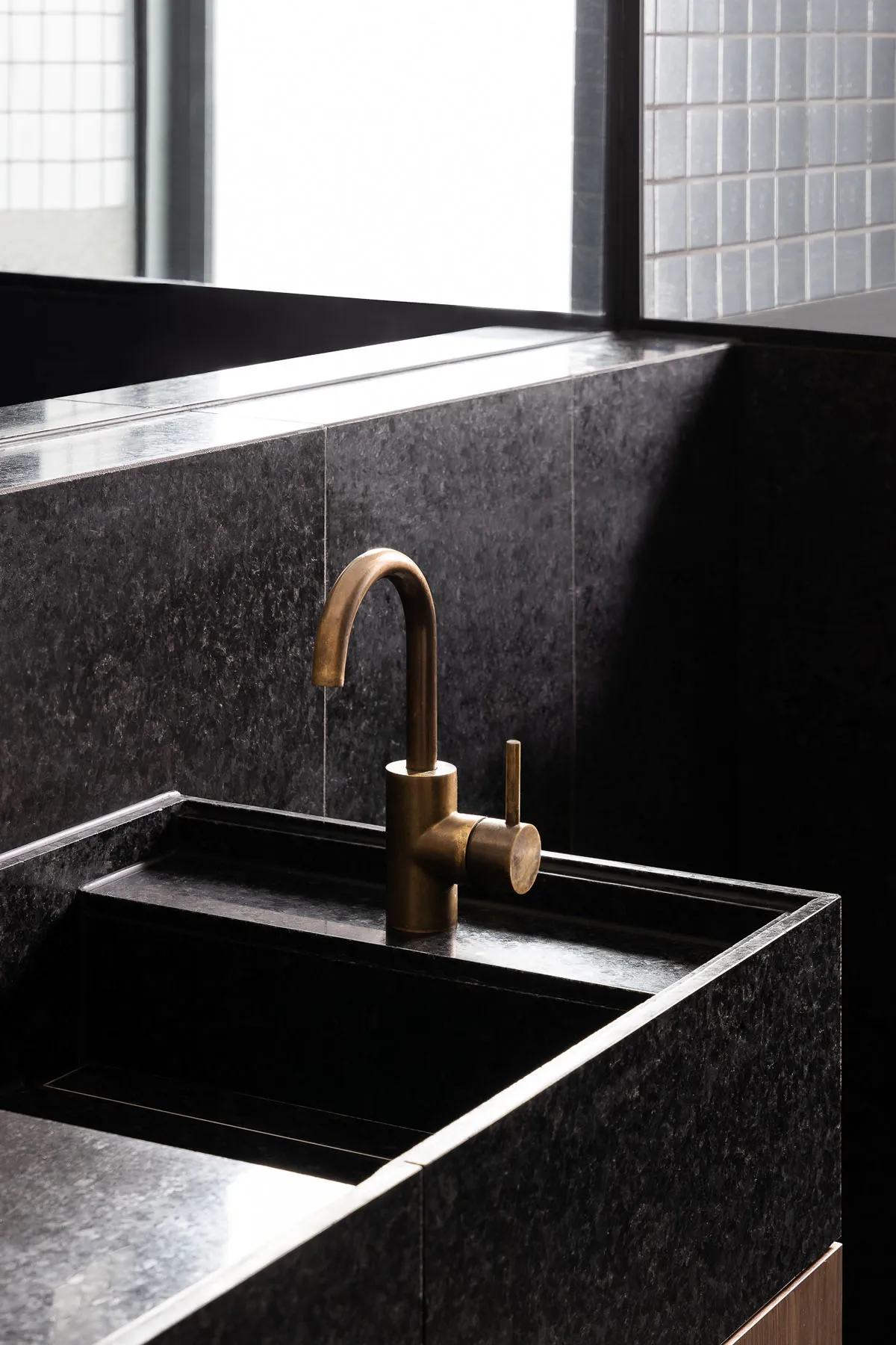 A modern, industrial-style bathroom featuring a black granite sink and faucet.
