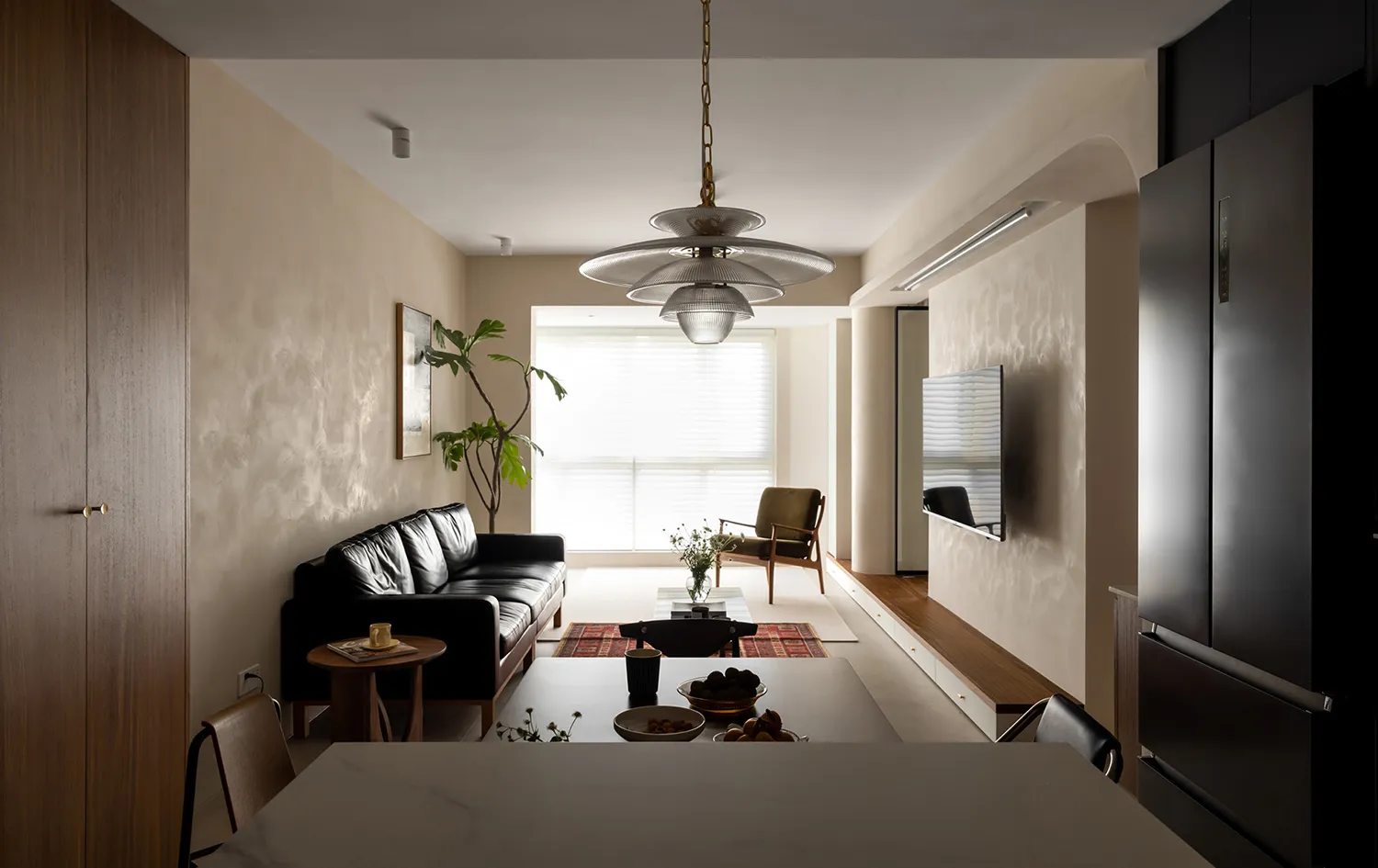 Modern living and dining room with leather sofa, glass coffee table, and wooden flooring.