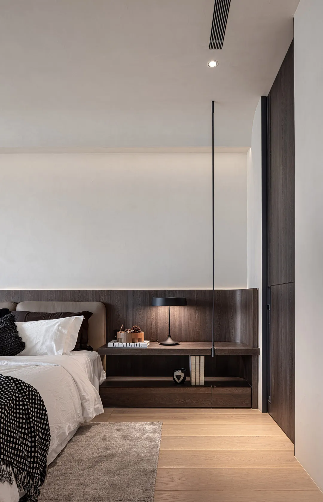 A minimalist bedroom featuring wooden paneling on the wall and ceiling, a white bed with brown and black accents, and a woode