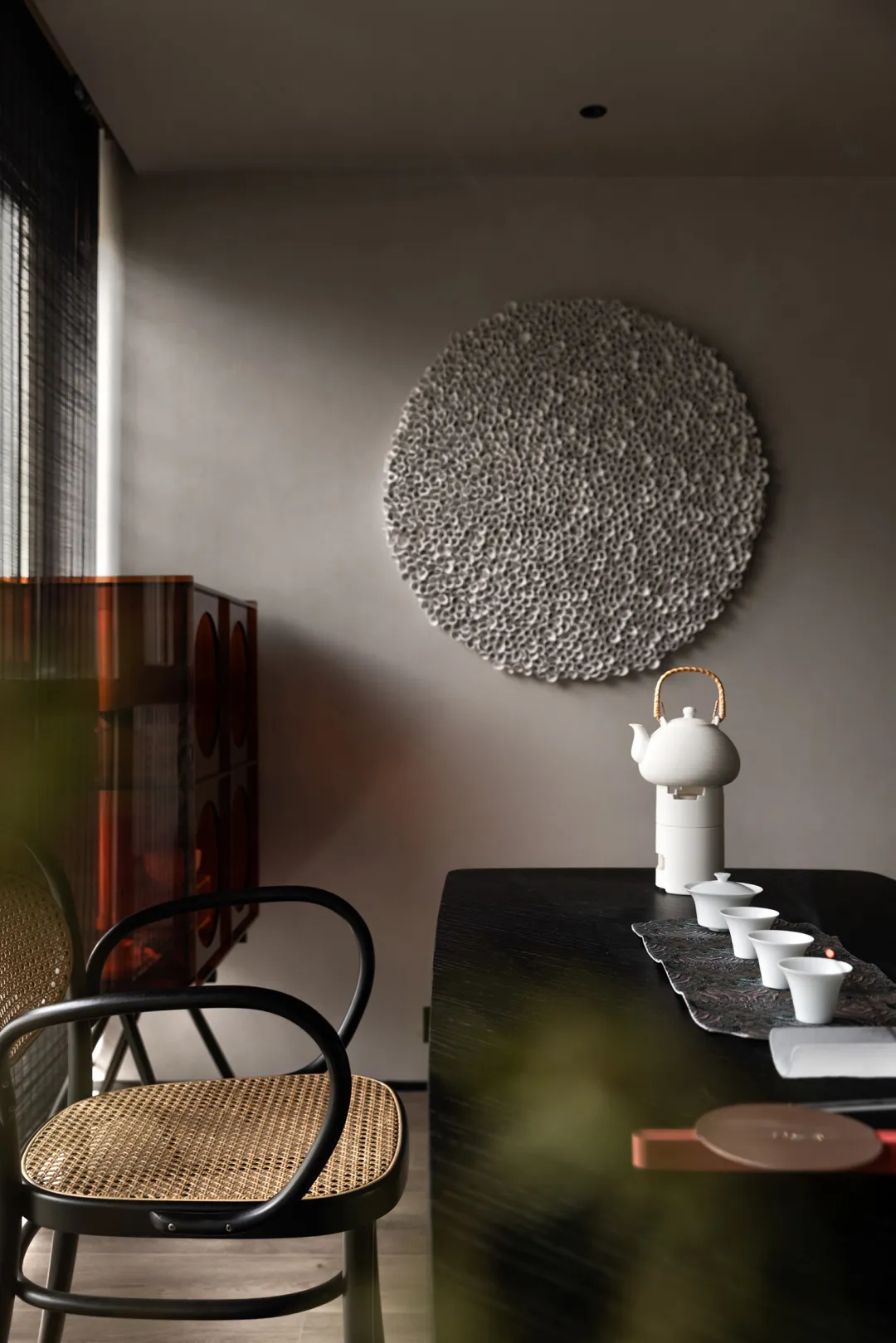 Modern living room with minimalist design featuring wood, rattan, and ceramic elements.