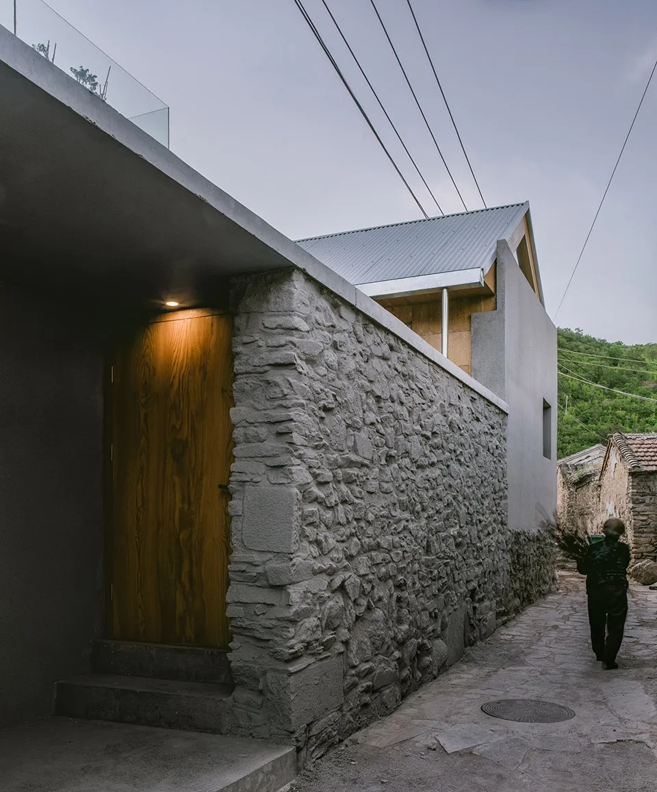 Modern building exterior featuring stone walls and a wooden door.