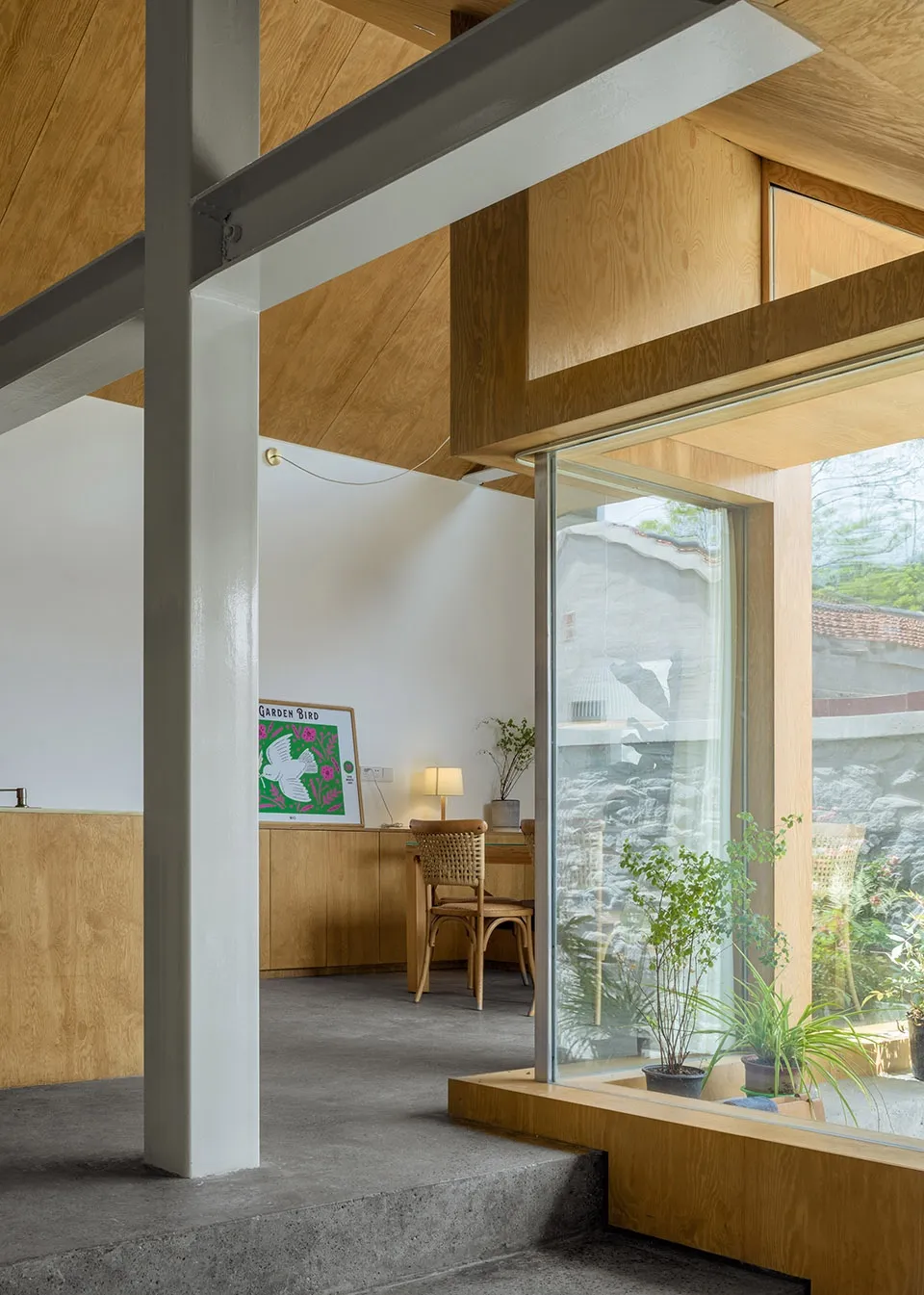 A modern home office with wooden walls, concrete floor, and a desk with a lamp and a chair.