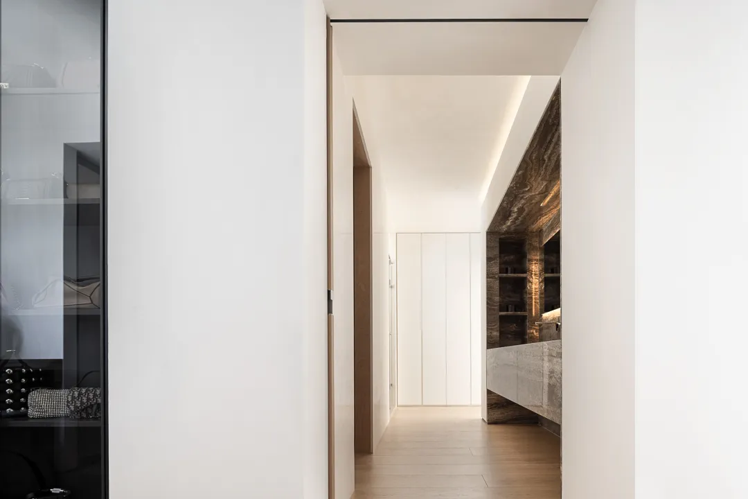 A minimalist interior space featuring wood, glass, and marble materials.