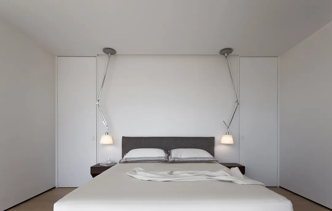 A minimalist white bed with a gray headboard in a modern bedroom setting.