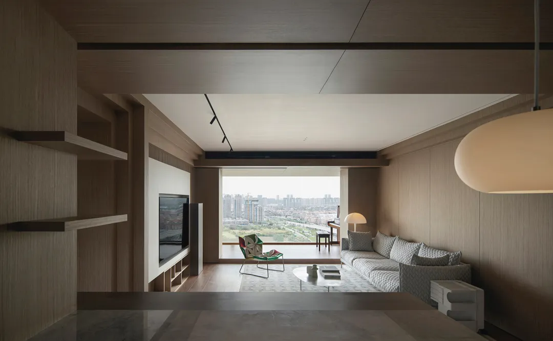 Modern living room with wooden furniture and a large window overlooking a cityscape.
