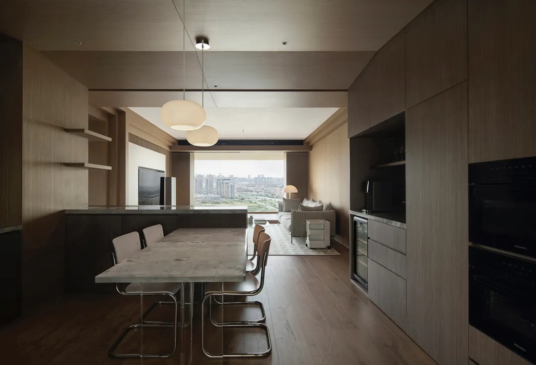 Modern apartment featuring a stone-top dining table and minimalist furniture, with a view of the cityscape.