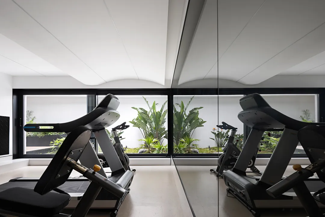 Minimalist fitness center with metal treadmills and glass walls.