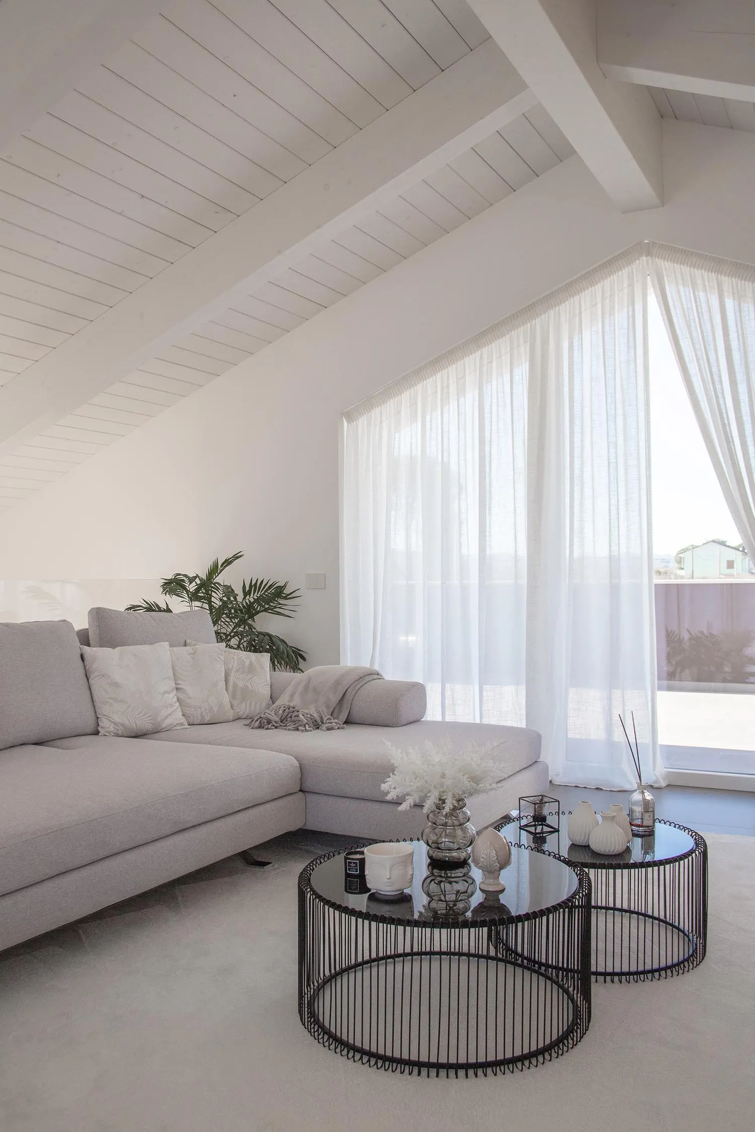 A spacious, minimalist living room featuring a large sectional sofa adorned with white cushions, positioned in front of a lar
