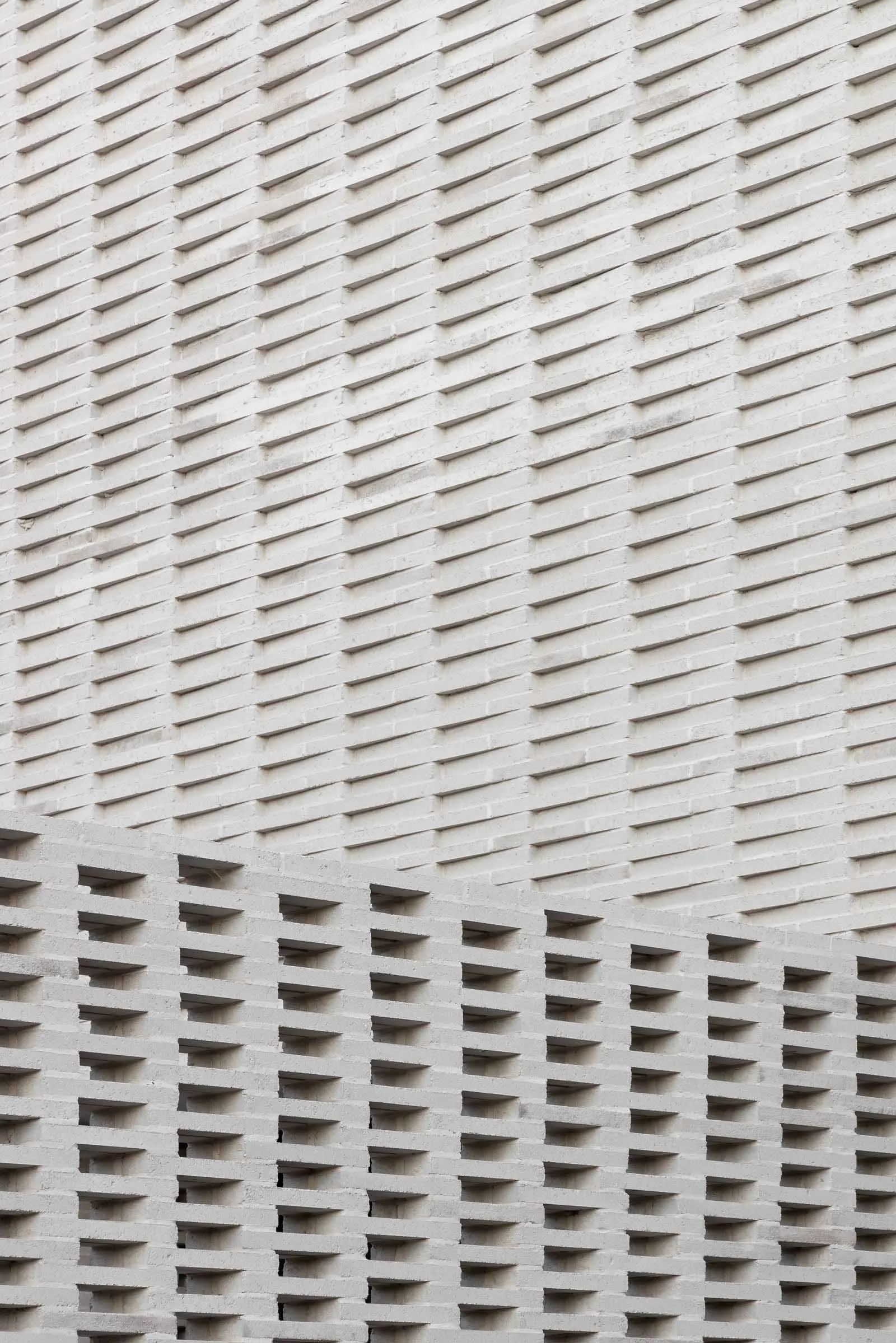 A detailed view of modern architecture featuring a repetitive, geometric pattern made of concrete bricks.