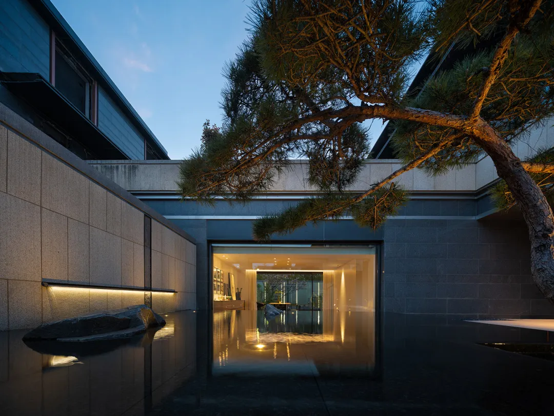 A minimalist residential home featuring concrete and glass materials at dusk.