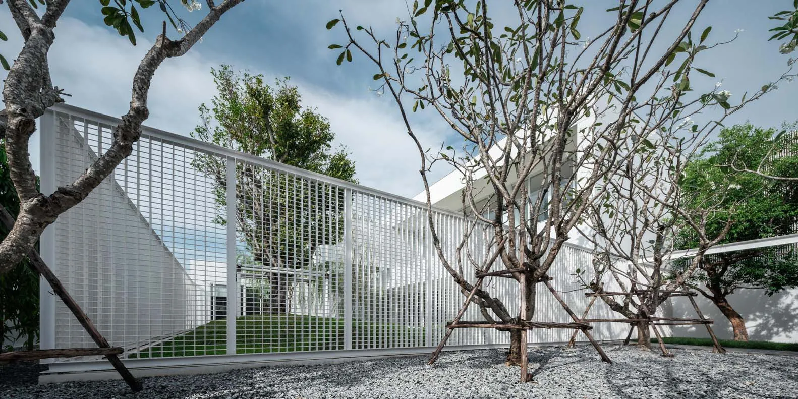 Modern residential design featuring metal fencing, concrete patio, and gravel ground cover.