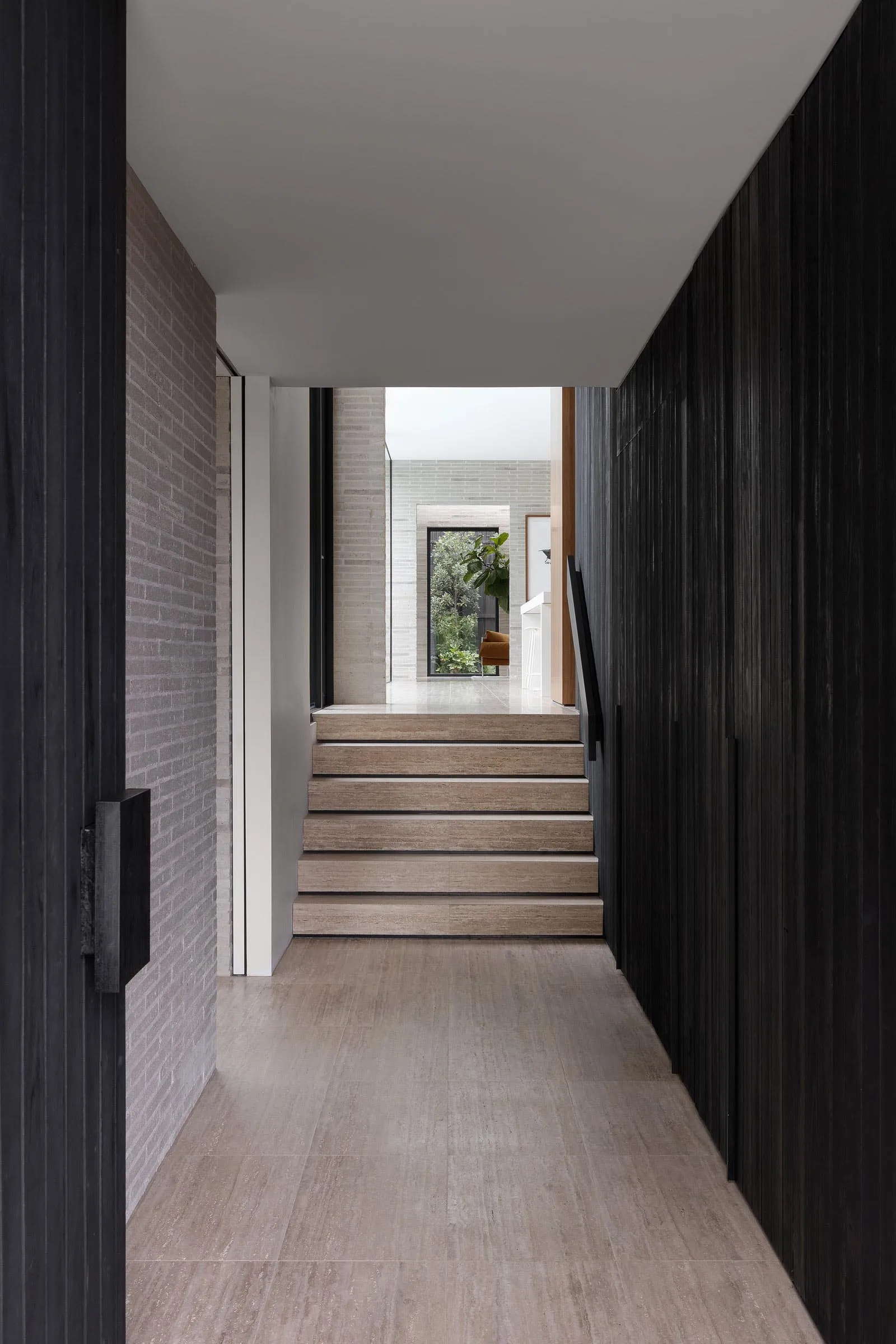 Modern interior featuring wooden staircase with white walls and black accents.