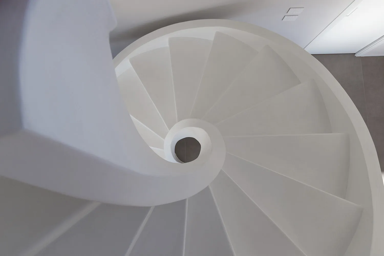 A minimalist white spiral staircase constructed from concrete.