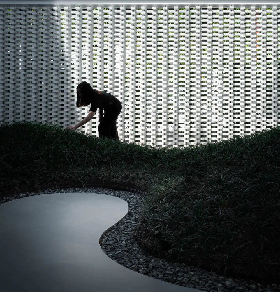 極簡花園中,一條弧形混凝土步道穿過綠意與礫石之間。