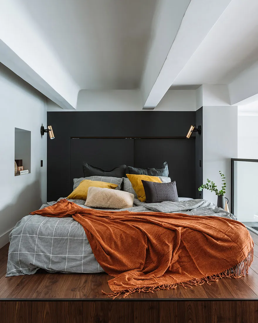 A cozy modern bedroom with a bed and wooden floor at night.