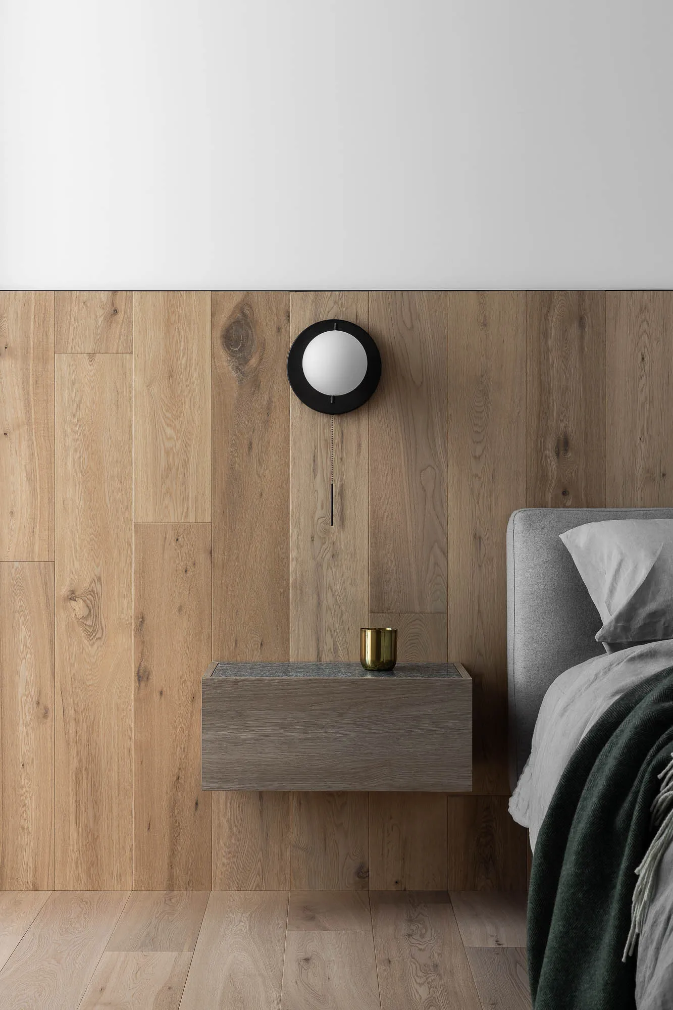 Modern minimalist bedroom with floating nightstand, wooden floor, and wall-mounted lamp.