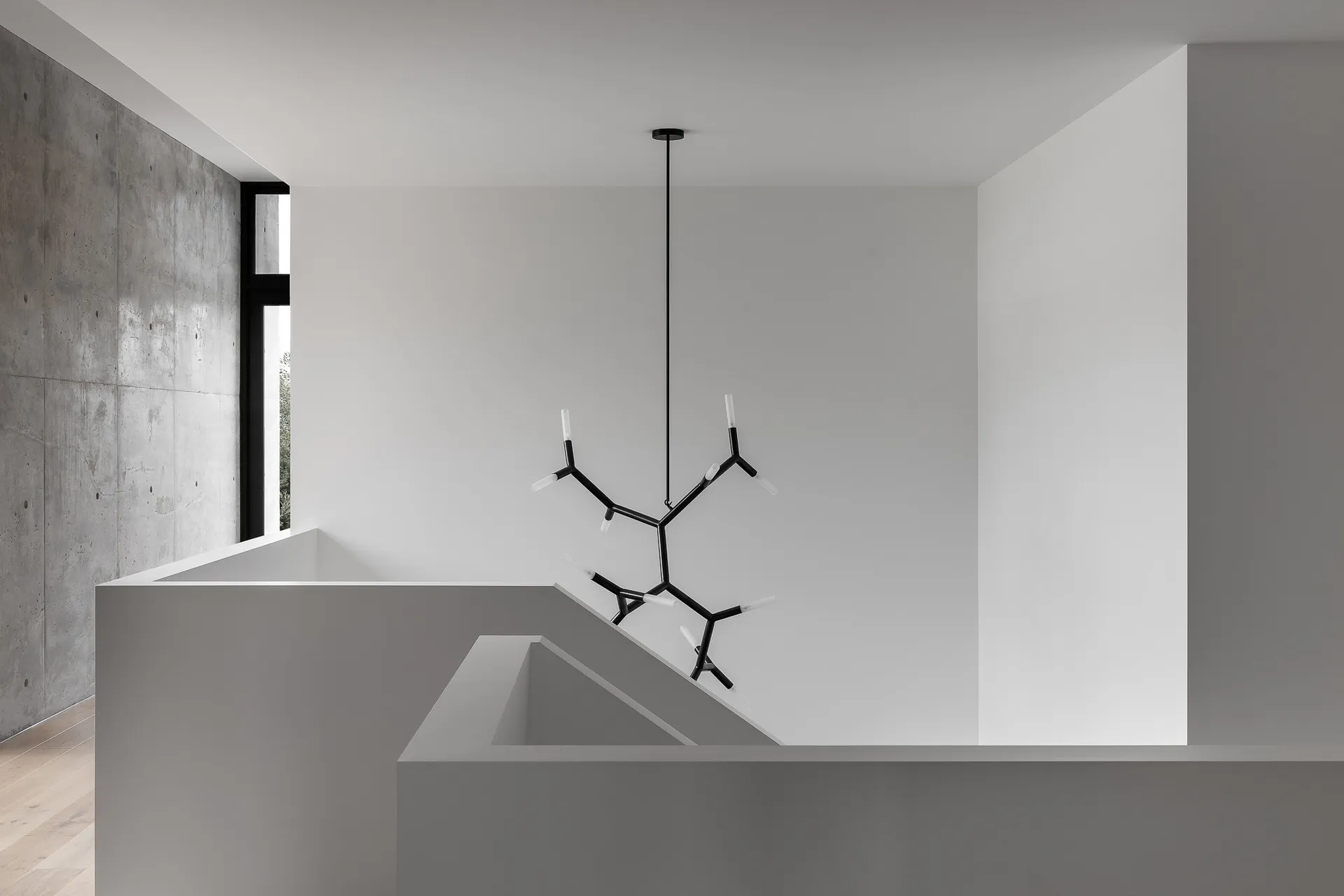 Modern interior with minimalist design, featuring concrete and white walls, and a unique lighting fixture.