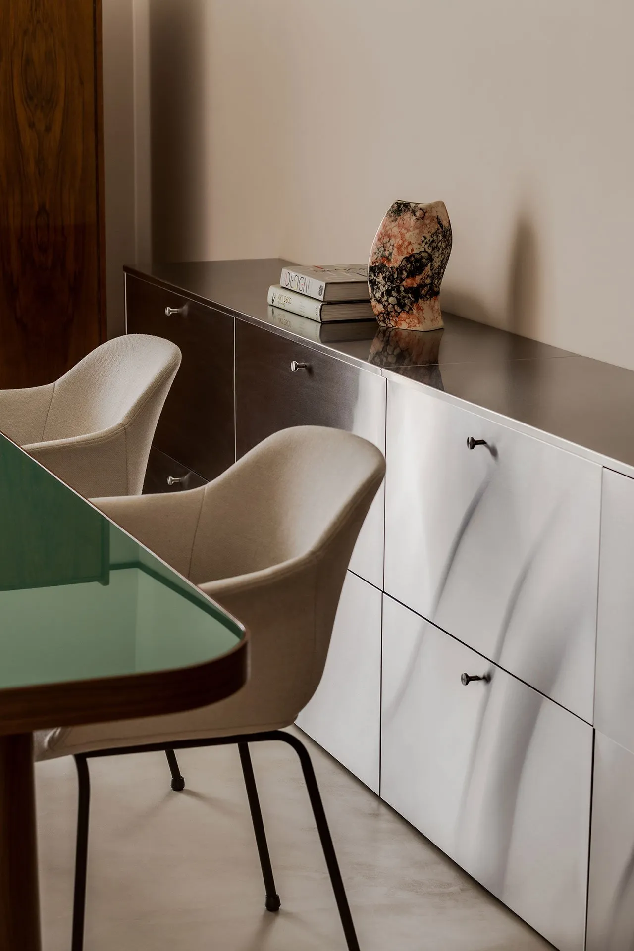 A minimalist furniture setup featuring metal cabinets and chairs, with books and a vase on top of the cabinets.