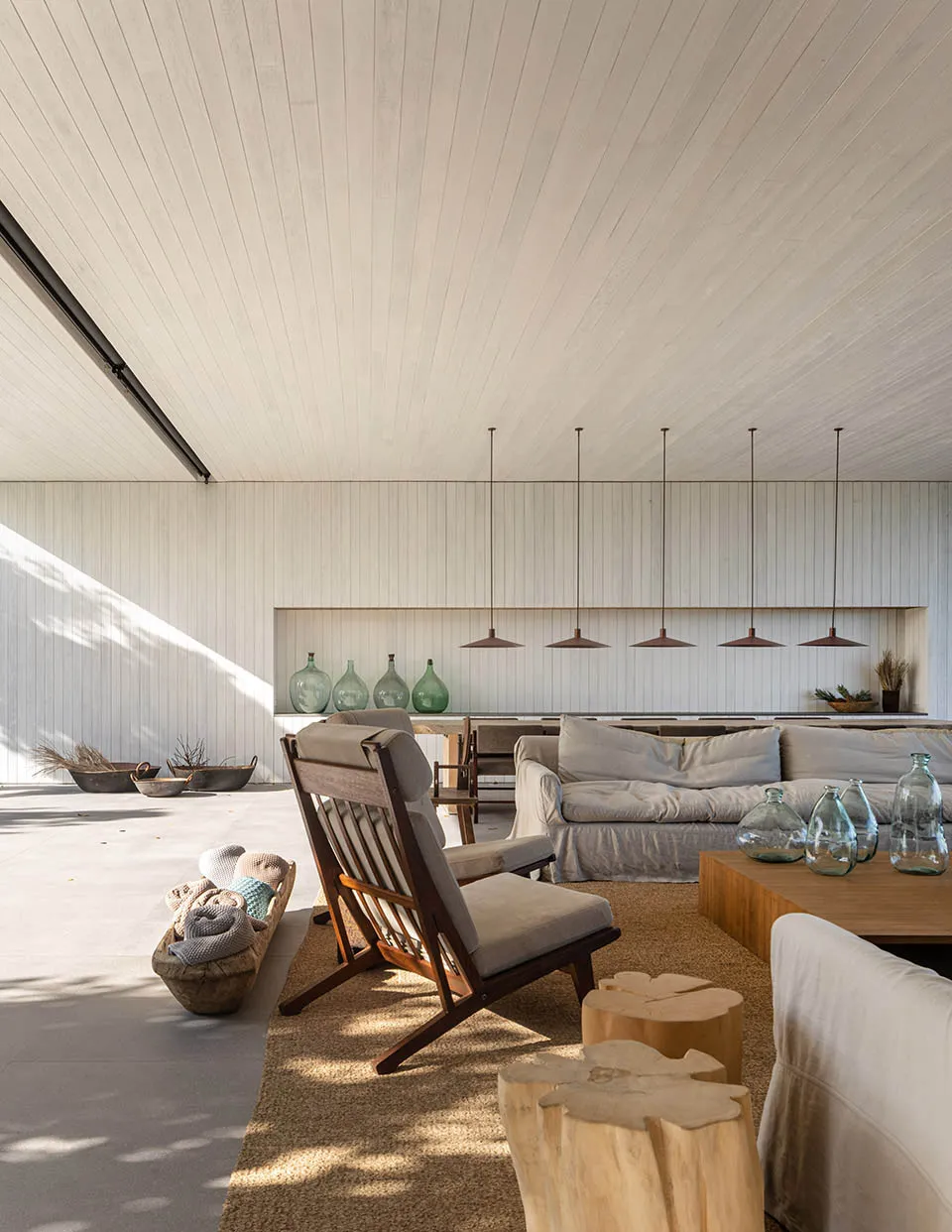 A modern minimalist living room with stone flooring, wooden furniture, and concrete walls.
