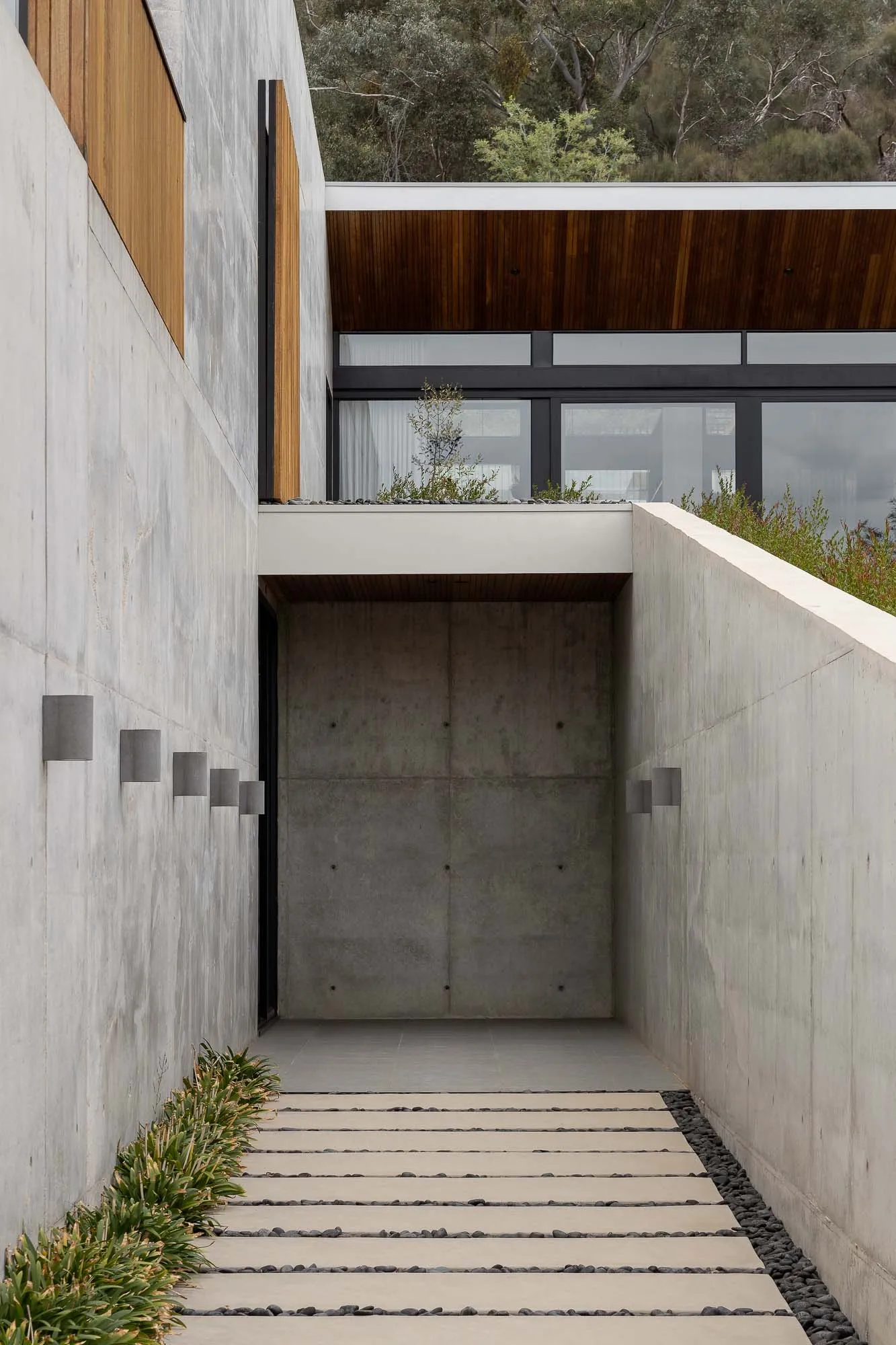 Modern entrance pathway leading to a concrete staircase, featuring minimalist design and sleek lines.