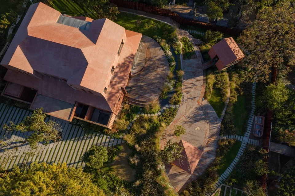 Aerial view of a modern house with brick exterior featuring a circular driveway and garden.