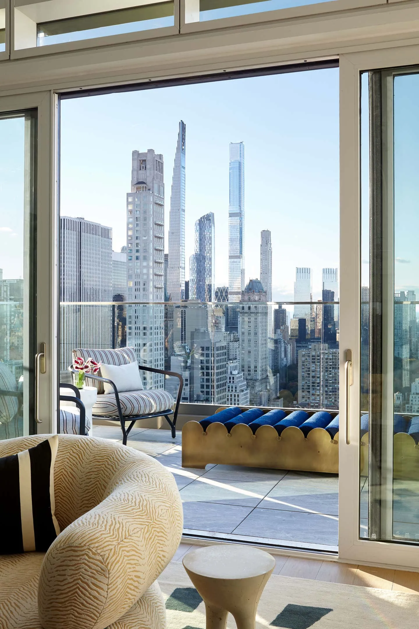 Modern interior design featuring a balcony with glass and metal details, offering a panoramic cityscape view.