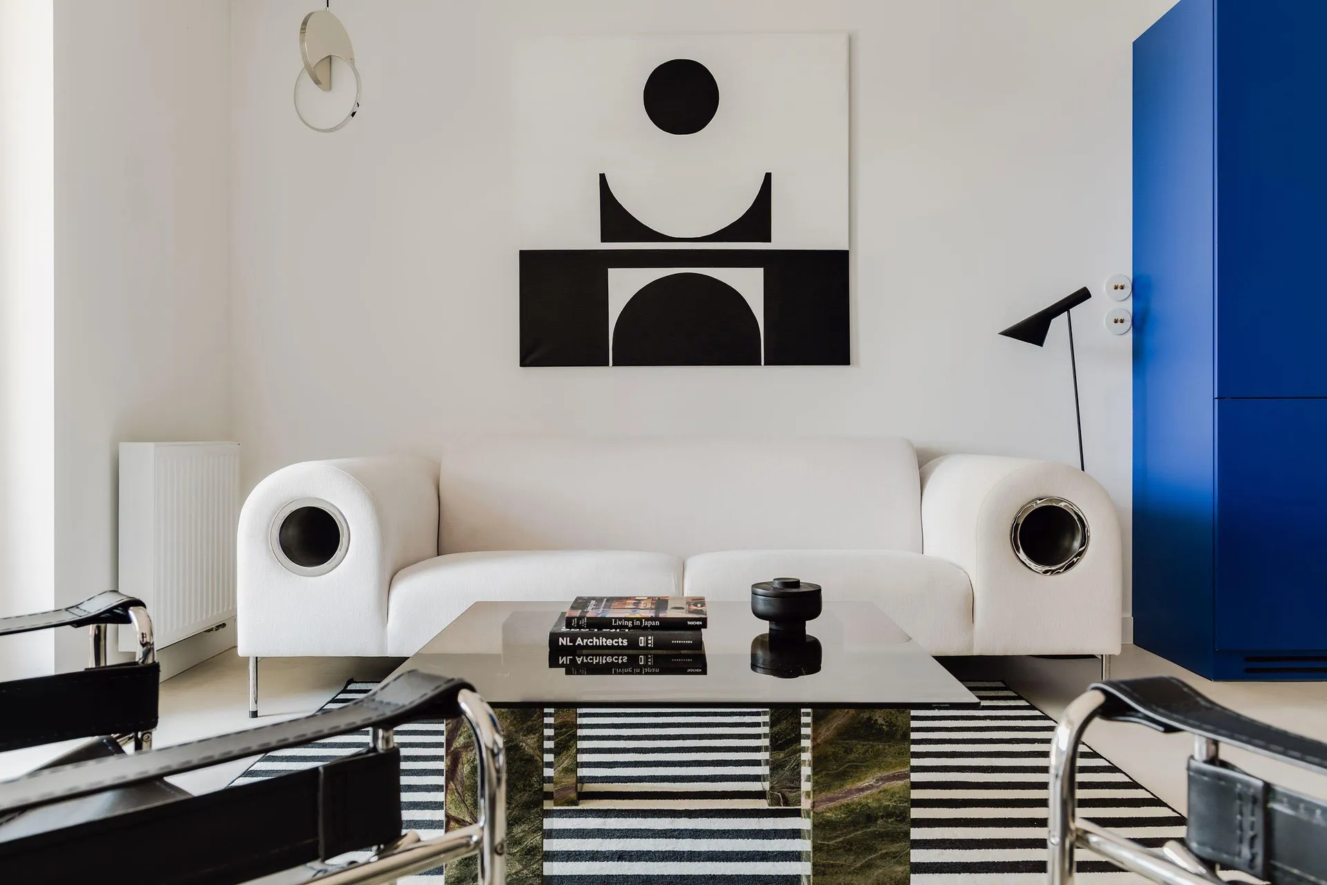 A modern living room with a white sofa, black and white geometric artwork, and a striped rug.