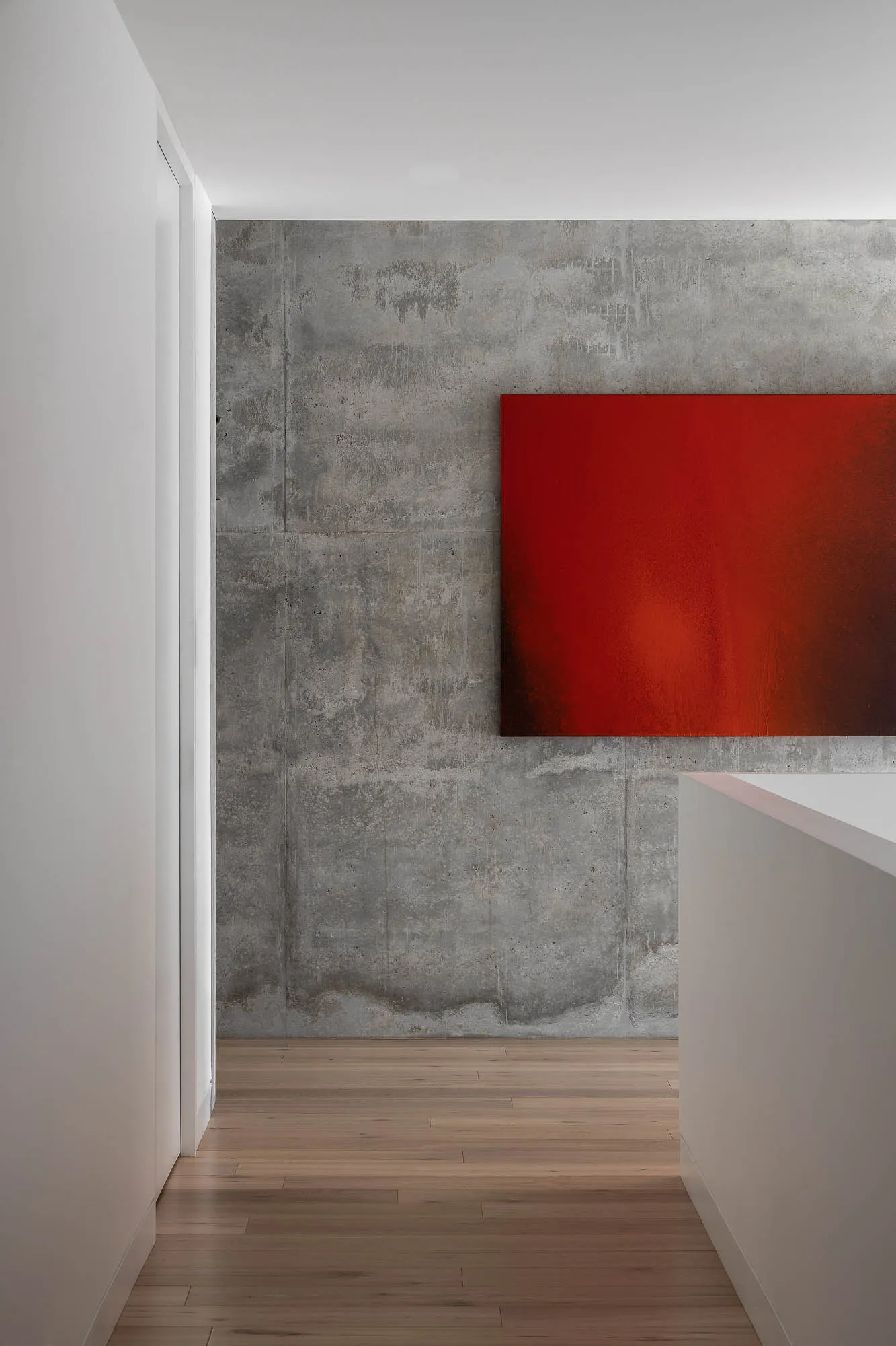 A minimalist interior featuring a modern red abstract painting on a concrete wall.