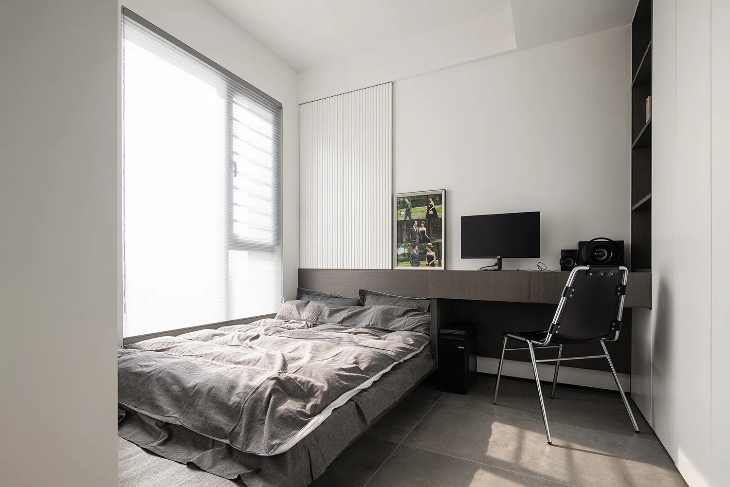A modern bedroom with grey bedding and a minimalist design.