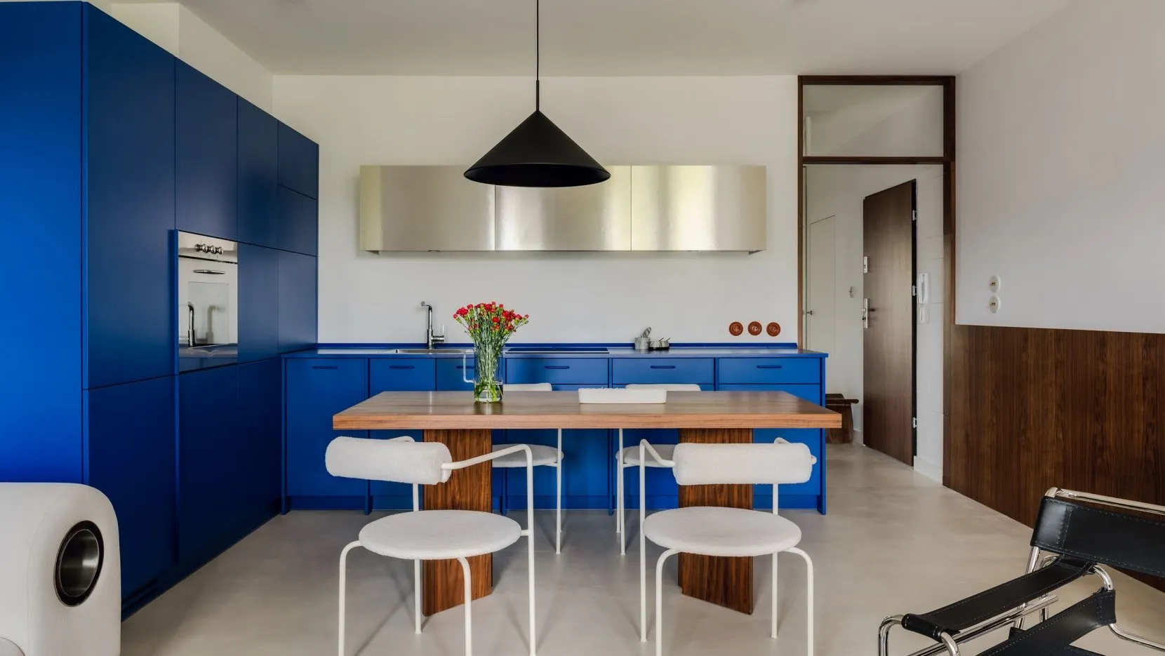 Modern residential kitchen with blue cabinets and a wooden dining table.