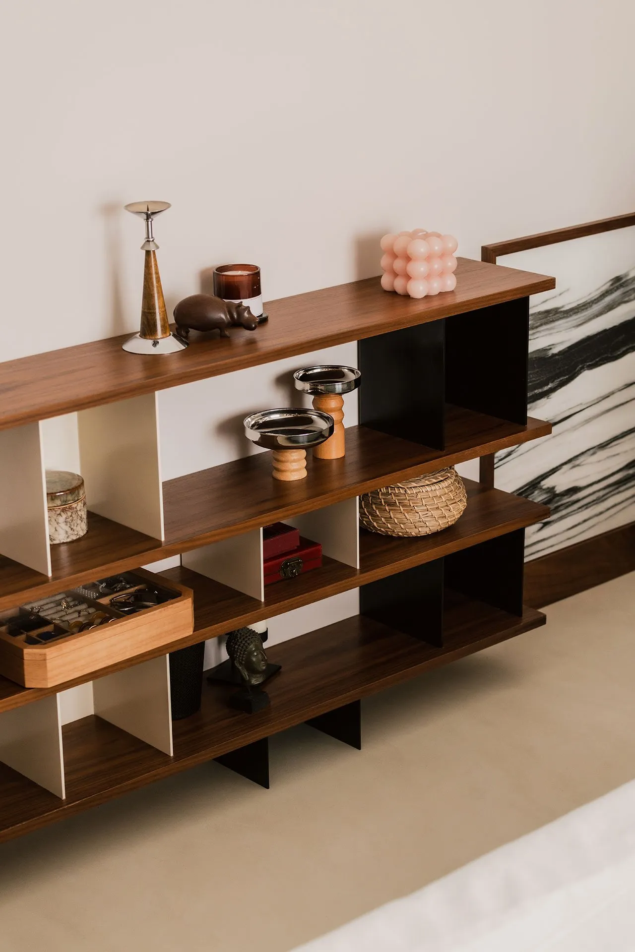 A modern minimalist wooden shelf with various decorative items and storage compartments.