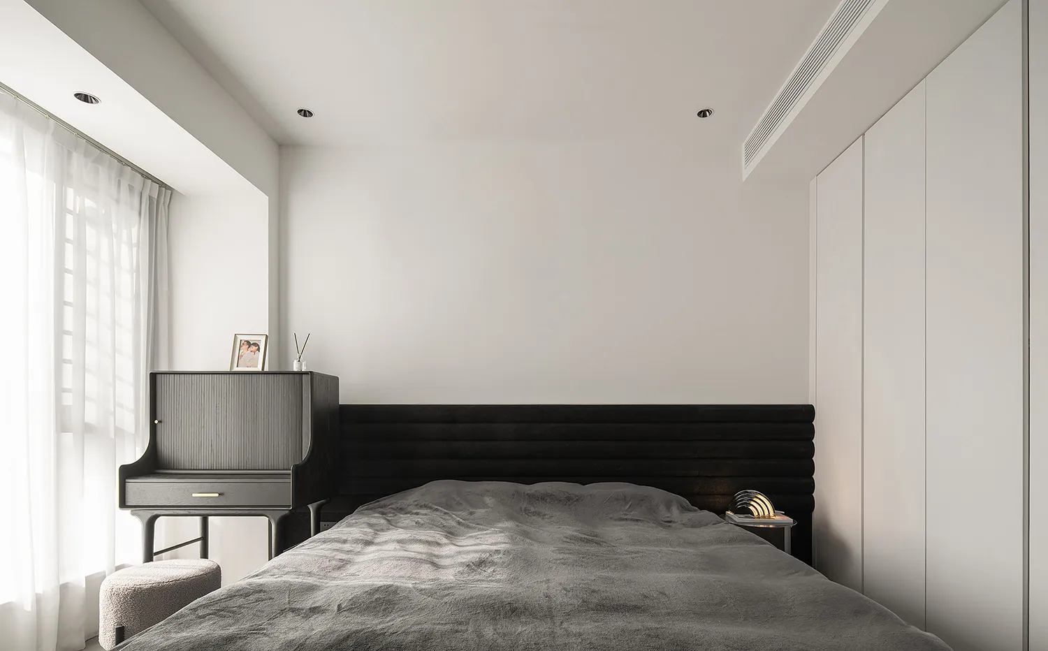 Minimalist bedroom with black furniture and wooden headboard