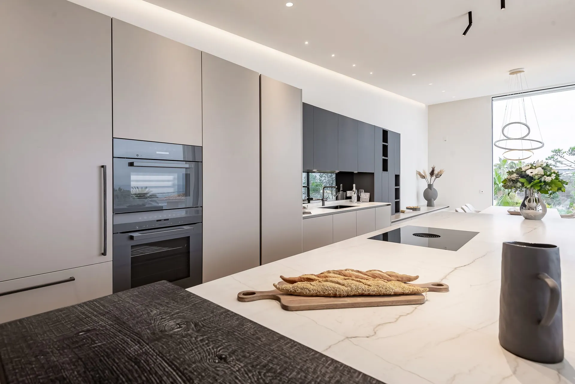 Modern, minimalist kitchen featuring white marble countertops and stainless steel appliances with a sleek, contemporary desig