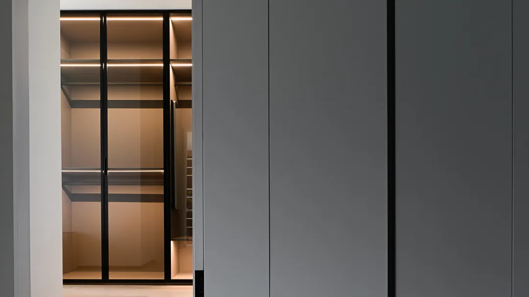 Modern minimalist closet featuring glass doors and shelves.