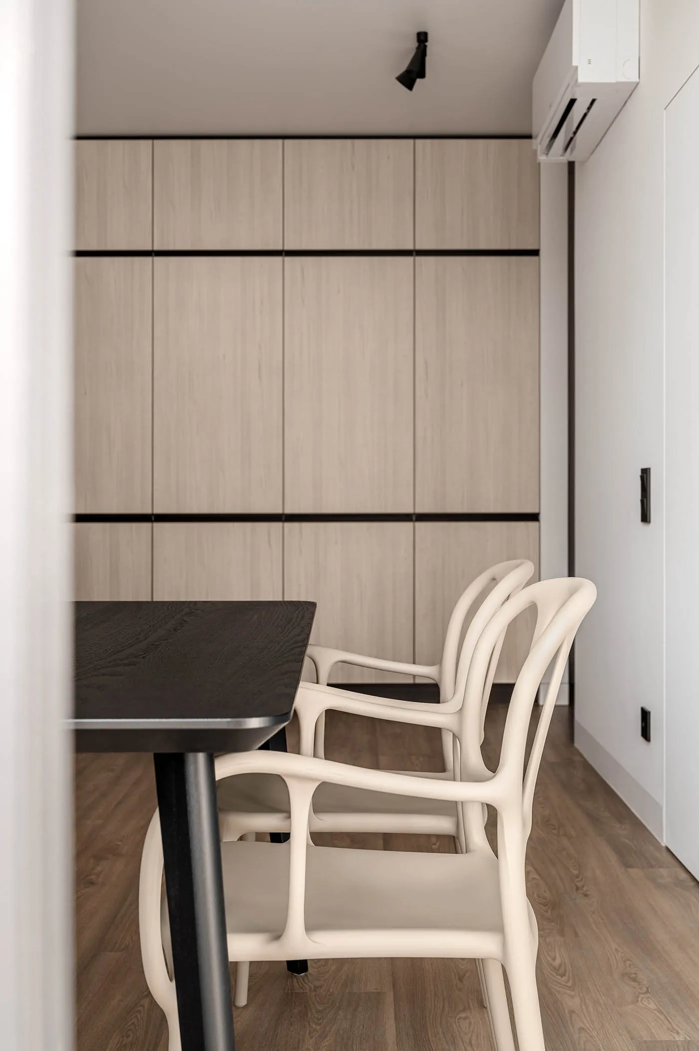 Modern minimalist dining room with wooden furniture and a sleek, dark dining table.