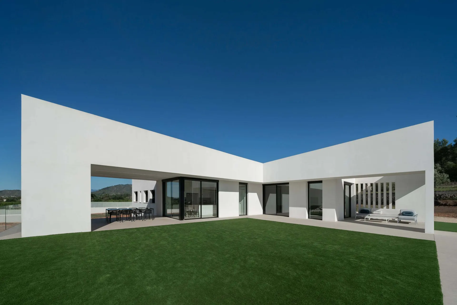 A modern concrete villa with large windows and a spacious outdoor area.