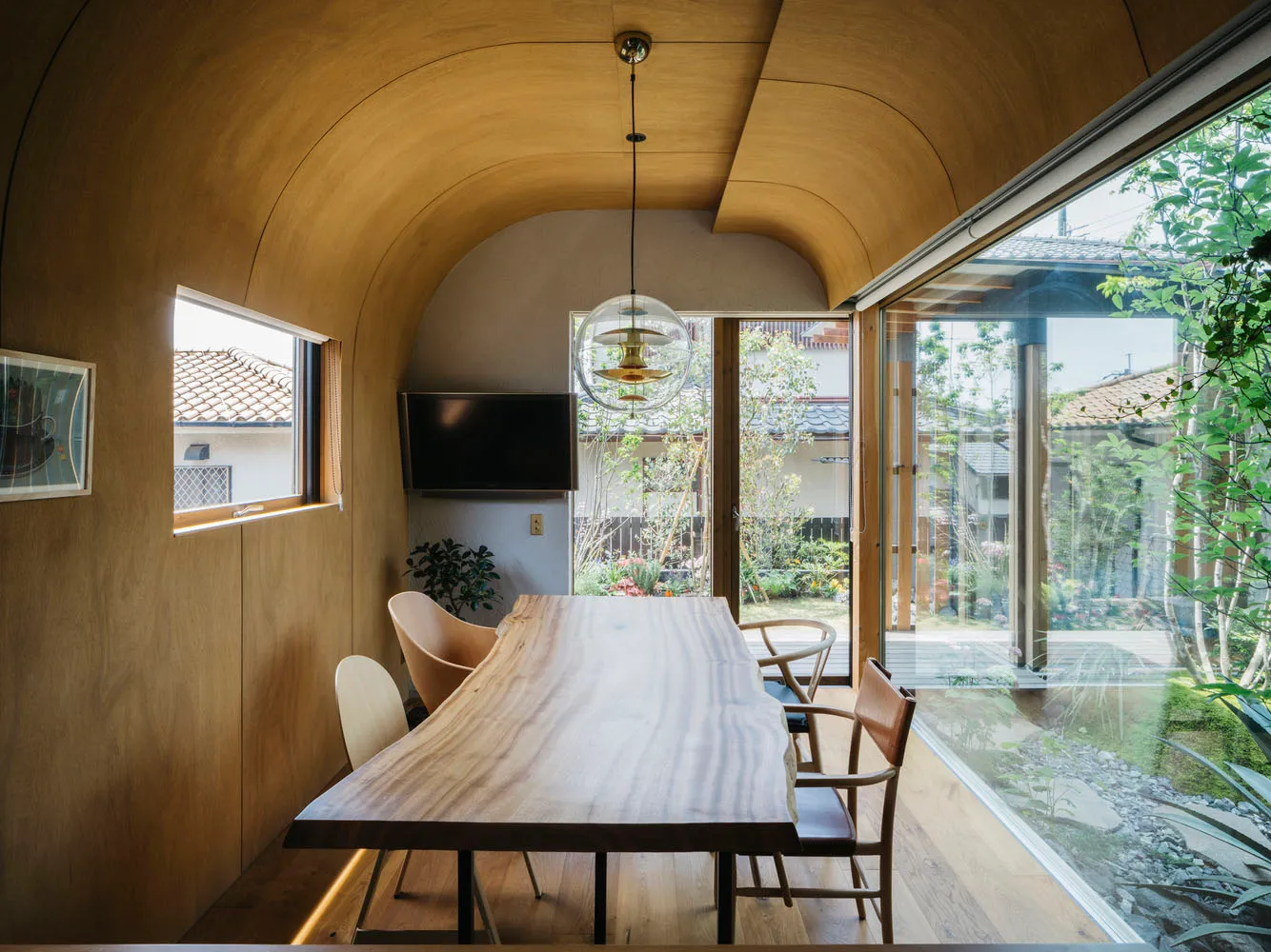 A modern dining room featuring a wooden table, chairs, and a hanging light fixture with a glass globe.