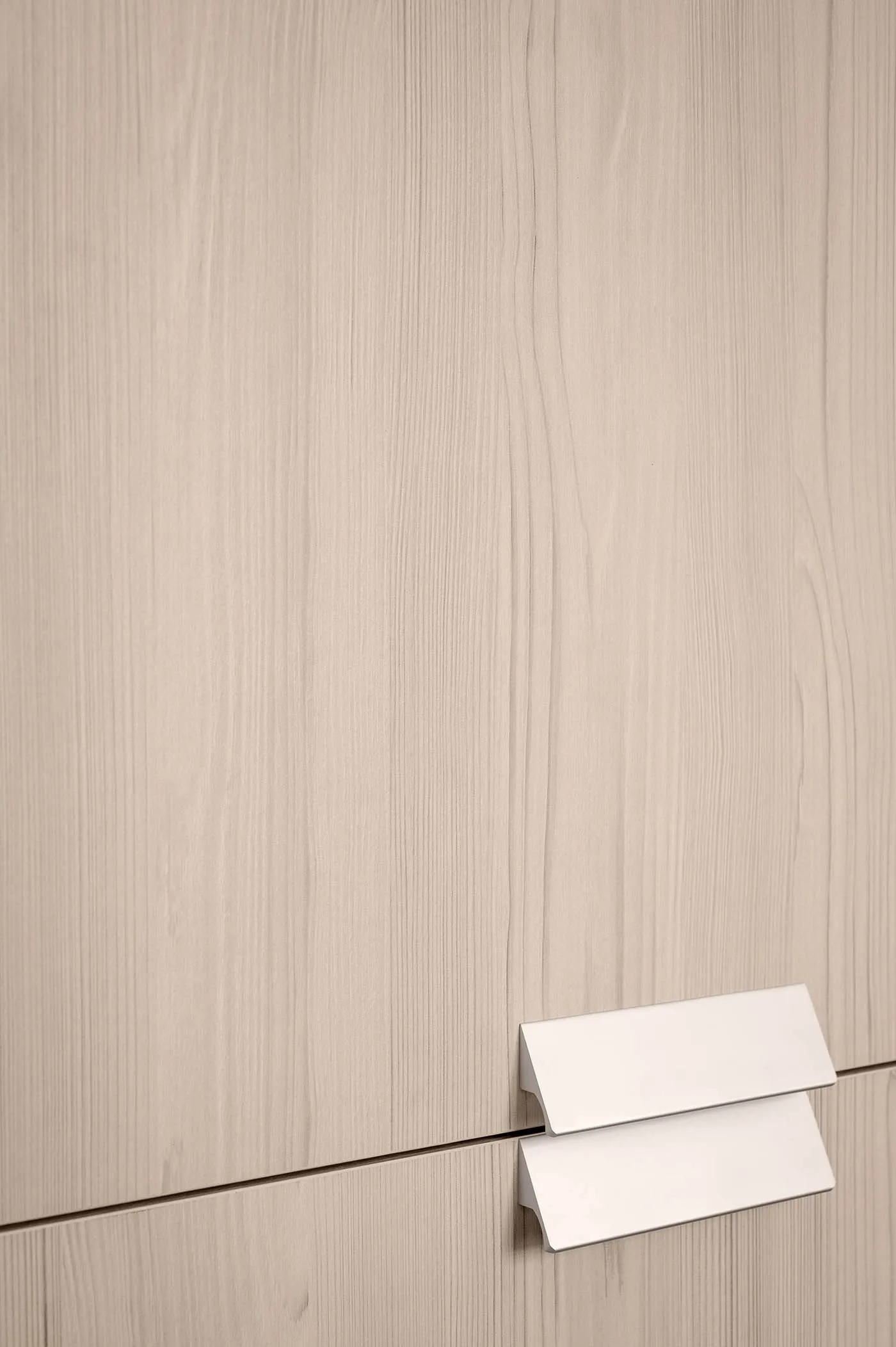 A close-up view of a modern minimalist wooden cabinet with a simple metallic handle