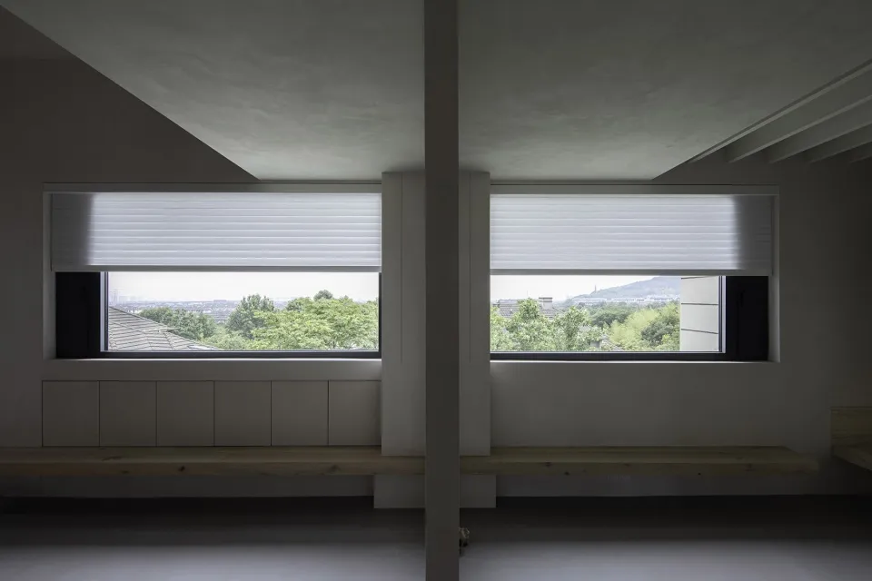Modern architectural view with metal blinds covering large windows showcasing outdoor scenery.