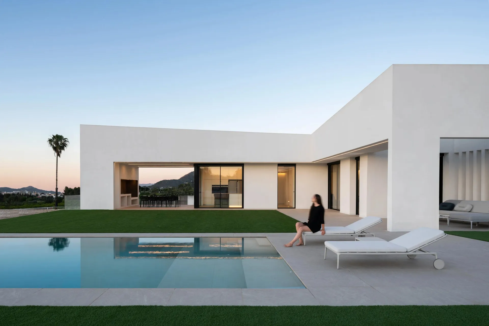 Modern minimalist home exterior with white concrete exterior walls and a large swimming pool.
