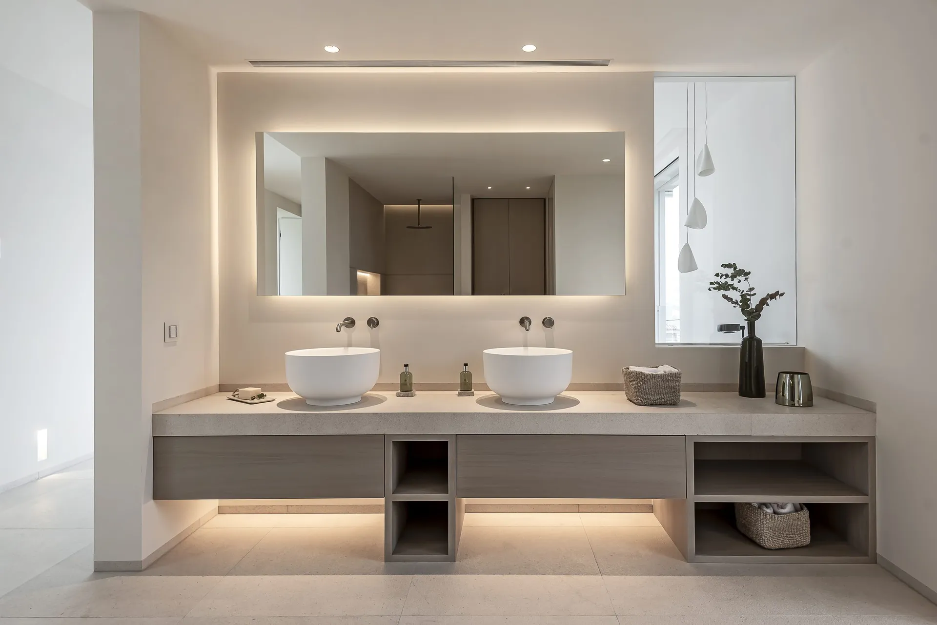 A minimalist bathroom with a double vanity and concrete finishes.